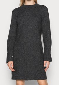 Robe tricotée gris foncé avec un col montant, des manches longues et des détails aux poignets. Le tissu a une finition douce et texturée.