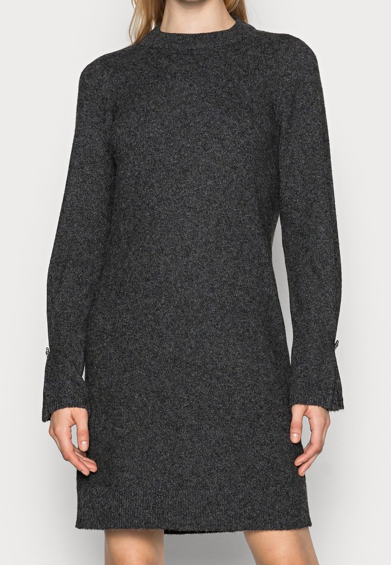 Robe tricotée gris foncé avec un col montant, des manches longues et des détails aux poignets. Le tissu a une finition douce et texturée.