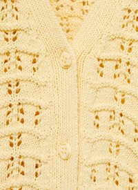 Ljusgul stickad cardigan med ett mönster av textur och öppna detaljer, fastsatt med en rund krämfärgad knapp framtill.