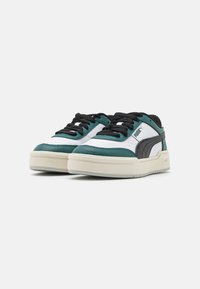 Scarpe sportive con una combinazione di pelle bianca, verde scuro e accenti neri, caratterizzate da un design testurizzato e una suola spessa di colore crema.