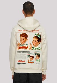 Cremfarbene Kapuzenjacke mit einem vintage Kellogg's Corn Flakes-Werbung. Das Design umfasst farbenfrohe Illustrationen von Kindern und retrotypografische Elemente.