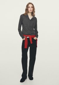 Gray long-sleeve button-up shirt with a collar, paired with black pants and a red sweater tied at the waist. Smooth texture and relaxed fit.