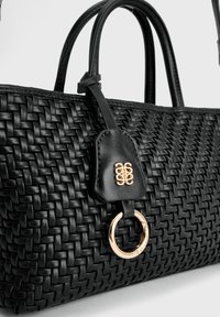 Zwarte geweven leren handtas met dubbele handvatten, voorzien van een gouden ring en een leren label met een gouden embleem.