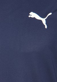 Námořnická modrá tričko s hladkou texturou, na hrudi s bílým logem Puma v skákací pozici. Klasický design s krátkými rukávy.