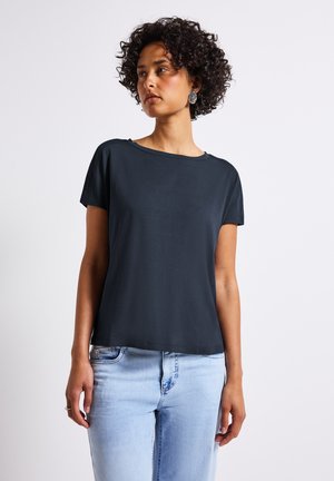 Donkerblauwe T-shirt met korte mouwen, een relaxte fit, een soepele textuur en een ronde halslijn, gecombineerd met lichtblauwe jeans.