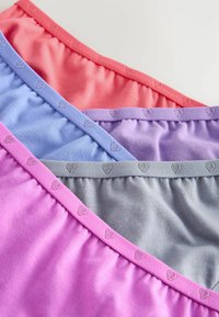 Quatre paires de sous-vêtements en tissu doux en corail, violet, bleu, gris et rose avec de petits motifs en forme de cœur le long de la ceinture.