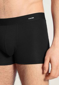 Zwarte katoenen boxershorts met een nauwsluitende pasvorm, voorzien van een soepele tailleband waarop de merknaam "CALIDA" prominent is weergegeven.