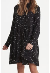 Abito nero a maniche lunghe con colletto button-down, caratterizzato da pois bianchi, vita arricciata e vestibilità ampia. Texture del tessuto morbida.