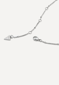 Zilveren ketting met een driehoekige hanger, gegraveerd met "Guess", zorgvuldig verbonden met ronde accenten en een musketon sluiting.