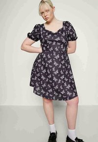 Vestido preto com mangas curtas balonê, apresentando uma estampa de borboleta branca. Forma godê, textura suave e decote arredondado.