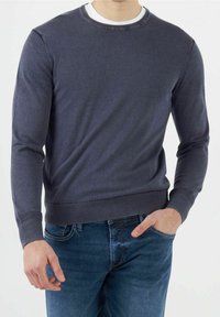 Maglione girocollo in cotone blu navy con polsini e bordo a coste, abbinato a jeans blu. Tessuto leggero con una consistenza liscia.