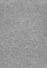 Pilkas megztas džemperis su švelnia tekstūra, turintis raukšlėtą apatinę dalį ir vienodą raštą visame paviršiuje. Šviesiai iki vidutiniškai pilkos spalvos.