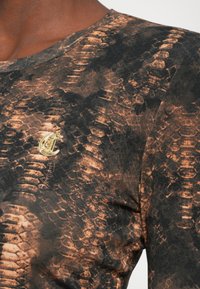 Long-sleeve shirt in black and brown snake print fabric. Features a round neckline and a gold logo detail on the chest.