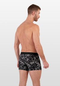 Černé boxerky s texturovaným květinovým vzorem v šedé barvě, s jednobarevným černým páskem. Krátký střih nohavic, hladký povrch.