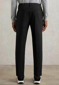 Zwarte op maat gemaakte broek met een slim fit, voorzien van twee achterzakken en een soepele stofstructuur. Draag met zwarte sneakers.