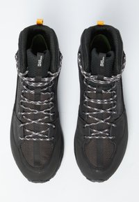 Schwarze Wanderschuhe mit strukturierten Mesh-Einsätzen, reflektierenden Schnürsenkeln und einer orangen Zuglasche. Enthält verstärkte Zehenkappen und Gummi-Außensohlen.