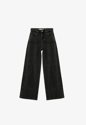 Schwarze weit geschnittene Jeans aus Denim, mit ausgefransten Kanten und silbernen Nieten entlang der Seitennähte. Hochsitzzender Schnitt.