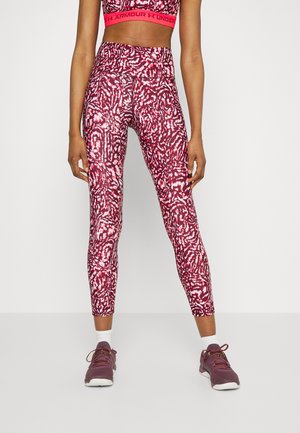 Leggings atléticos de color rojo y blanco con un patrón, hechos de un material elástico, combinados con un top corto a juego y zapatillas moradas.