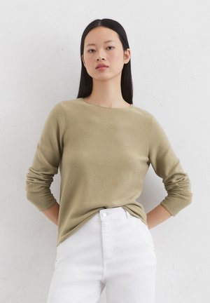 Olive green knit sweater with a crew neck and long sleeves, paired with high-waisted white jeans. Smooth texture, casual fit.