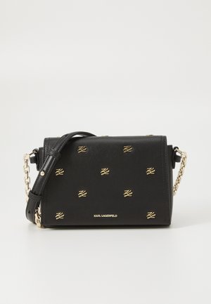 Must muströga mustra on mustast nahast, millel on kuldse logo aktsendid, kett rihm, ristkülikukujuline kuju, tekstureeritud pind ja klapp sulgemisega, millel on minimalistlik disain.