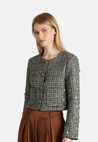 Grünes, strukturiertes Jackett mit kariertem Muster, runder Halslinie, Knopfleiste und zwei vorderen Taschen mit kontrastierenden Kanten.