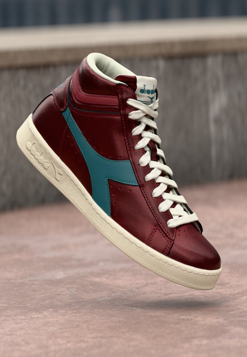 High-top sneaker in burgundy leather with teal accents, white laces, and a textured cream rubber sole. Features logo on the tongue.