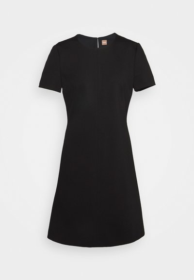 Robe noire à manches courtes avec un col rond et une fermeture éclair au dos. Silhouette simple en A avec une texture lisse et un design minimal.