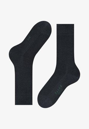 Granatowe skarpetki wykonane z miękkiej mieszanki bawełny, charakteryzujące się gładką teksturą, wzmocnionym palcem oraz subtelnym zielonym logo na podeszwie.