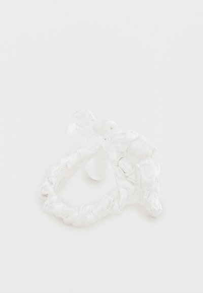 Anillo blanco con forma de cabeza de dragón, con detalles intrincados, textura suave y diseño de banda retorcida.