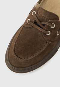 Pruun sametnahast king ümmarguse varbaosaga, pitsidega ja metallist silmadega. Kummist tald, õmmeldud detailid ja sile sisemine vooder.