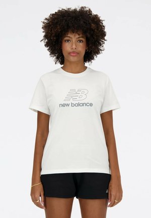 Hvid bomulds-T-shirt med korte ærmer, med en grå "new balance"-logo i midten. Parret med sorte shorts.