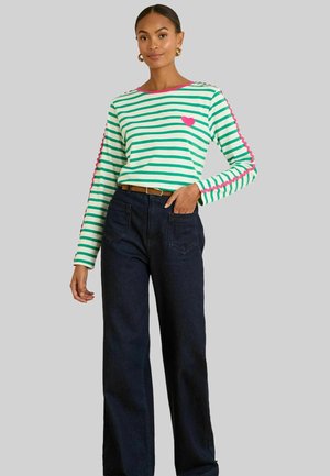 Gestreiftes langärmliges Oberteil in Grün und Weiß mit pinken Akzenten, das ein Herzdesign und gewellte Ärmeldetails aufweist. Kombiniert mit einer dunklen Jeans.