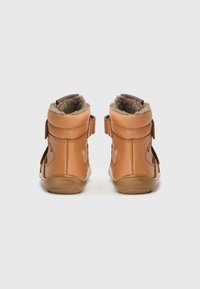 Braune Leder-Ankle Boots mit weichem Fellfutter, ausgestattet mit Klettverschlüssen und einer strukturierten Seitenfläche. Gummisohle für guten Halt.