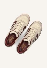 Beige sneakers met een fluffy textuur, bruine accenten en witte veters. Beschikt over een gevoerde inlegzool en een rubberen outsole voor grip.
