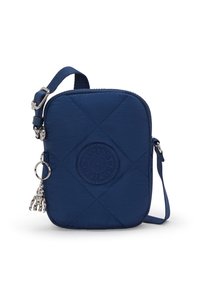 Sac bandoulière matelassé marine avec fermeture éclair, mettant en avant un patch logo rond et un charm décoratif en argent attaché à la sangle.