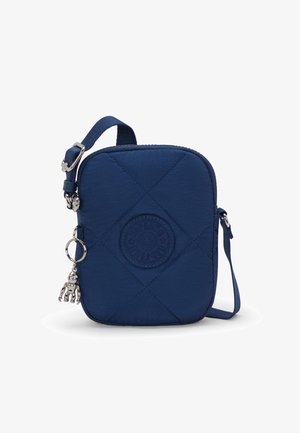 Borsa a tracolla trapuntata blu navy con chiusura a zip, caratterizzata da un patch rotondo con logo e un ciondolo decorativo in argento attaccato alla tracolla.