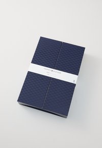 Sötétkék, texturált téglalap alakú doboz, fehér szalaggal, amelyen a "Tommy Hilfiger" felirat található, öt pár terméket tartalmaz.