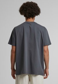 Šedé bavlněné tričko s uvolněným střihem, kulatým výstřihem a krátkými rukávy. Hladká textura, minimalistický design a rovný lem.