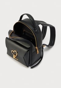 Μαύρο δερμάτινο σακίδιο με χρυσό κλειδαριά σε σχήμα καρδιάς, μπροστινή τσέπη, φερμουάρ στο κεντρικό διαμέρισμα και ρυθμιζόμενους επενδεδυμένους ιμάντες.