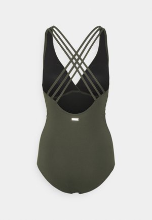 Yhdistelemätön uimapuku tummanoliivinvihreänä, syvällä V-kaula-aukolla ja ristikkäisillä naruilla selässä. Omistaa sileän kankaan ja minimalistisen muotoilun.
