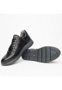 Zapatillas de cuero negro con un acabado liso, que presentan cordones, un cuello acolchado y una suela de goma gris duradera con un patrón texturizado.