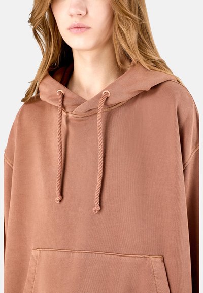 Overmaatse hoodie in een gedempt terracottakleur, met een voorzak, trekkoorden en zachte, gestructureerde stof.