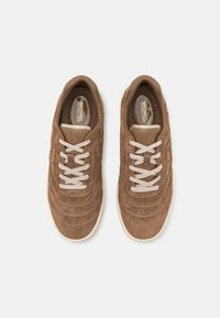 Paire de baskets Michael Kors en daim marron avec lacets beige et semelles blanches vues de dessus sur un fond uni.