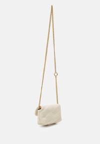 Piccola borsa a tracolla in pelle trapuntata color crema con una cinghia a catena dorata e un sottile logo di farfalla impresso sul davanti.