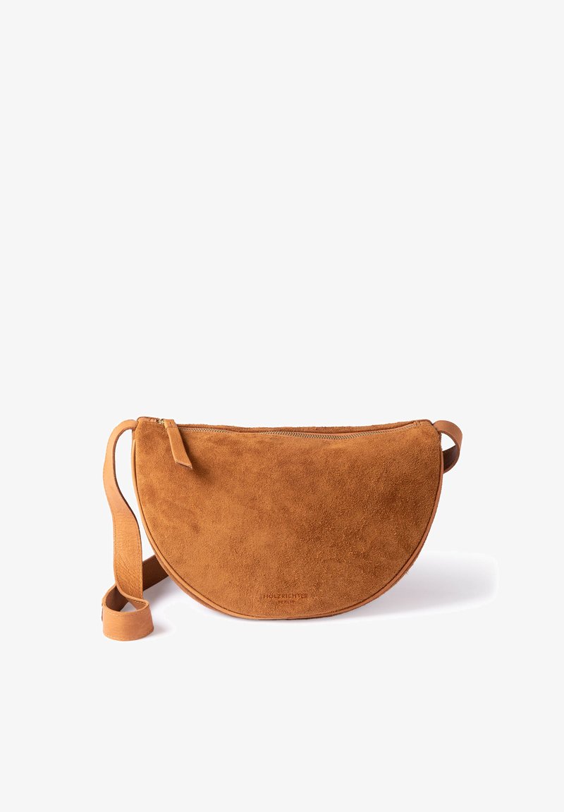Suede crossbody bag in brown with a half-moon shape, featuring a zipper closure and a wide strap. Smooth texture with minimal detailing.