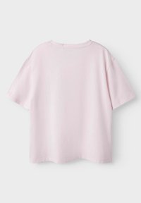T-shirt en coton rose clair, à manches courtes, avec un col rond, coupe décontractée et texture lisse. Aucune motif ou détail métallique visible.
