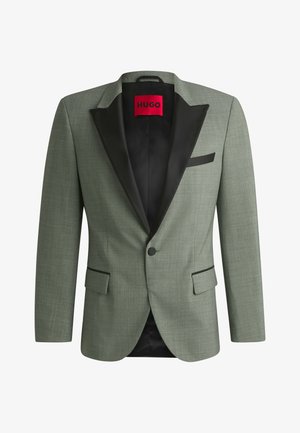 Grøn blazer med en sort satin revers, enkelt knaplukning, to frontlommer, tekstureret stof og indvendig foret med et rødt mærke.