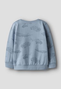 Jasnoniebieska bluza z wzorem szarych pojazdów w konturze, w tym samochodów, helikopterów i samolotów. Ściągacze na mankietach i u dołu.