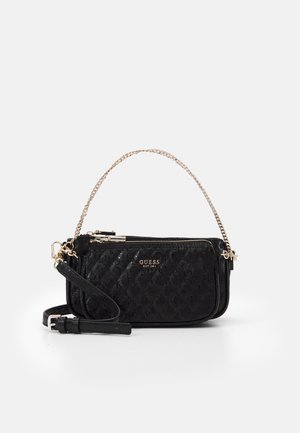 Sac à main Guess noir texturé avec poignée chaîne dorée, poche avant zippée et bandoulière réglable amovible sur fond blanc.