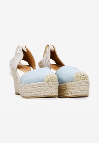 Alpargatas de cuña con parte superior de lona azul claro, correas de tobillo trenzadas en color beige y una plataforma de cuerda de yute con una puntera texturizada.